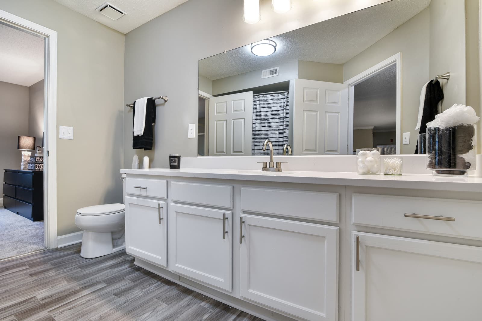 white shaker cabinets and wood-look flooring in model bathroom