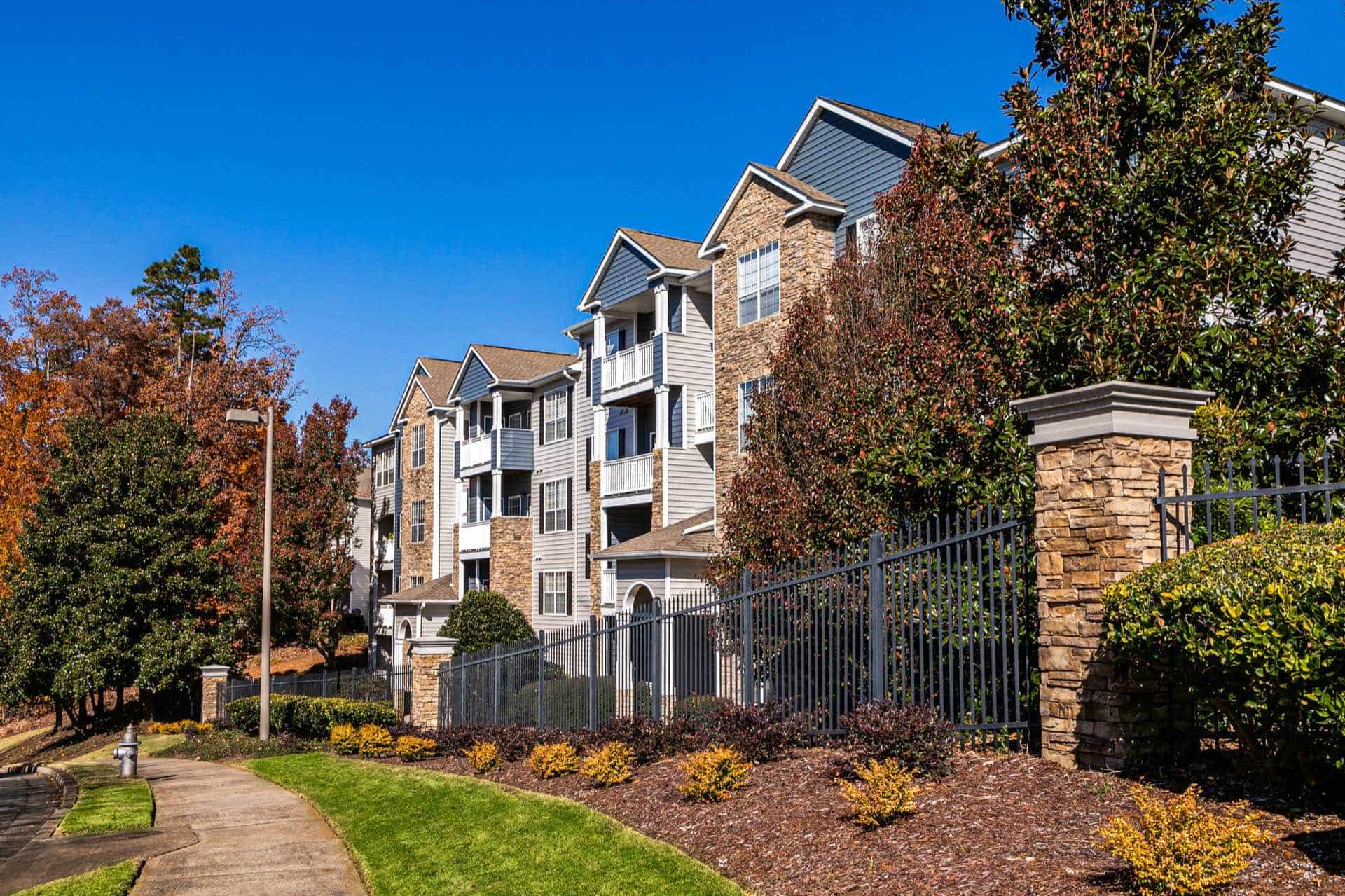 exterior view of apartment building with surround fence and sidewalk